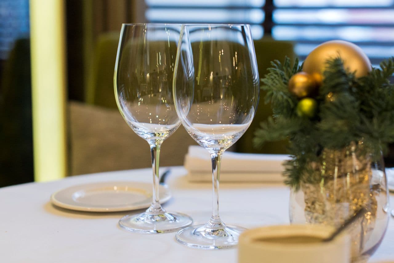 Elegant dukat julbord med vinglas och gyllene julkulor hos Le Rustique